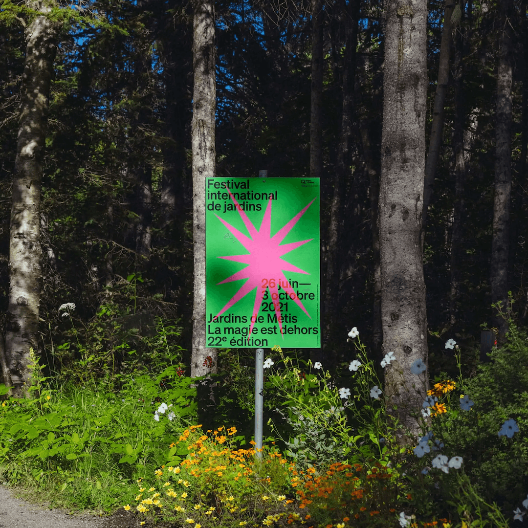 A poster of the International Festival des Jardins 2021 in situ amongst foliage, with a pink geometric shape intersecting the type over a green background.