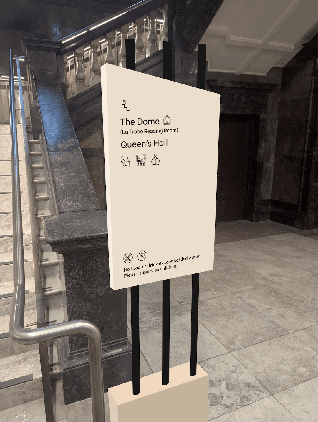 A mockup of a small signage totem in front of a staircase with directions to The Dome and Queen's Hall.